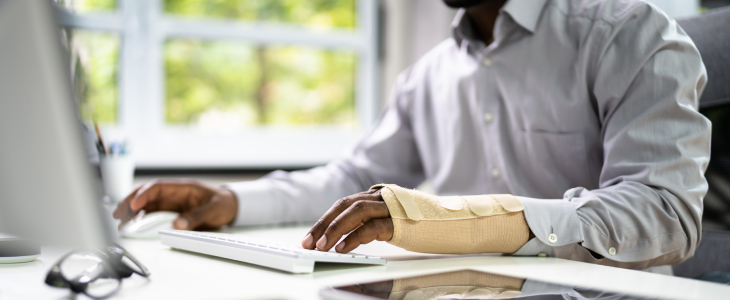 Man with a hurt arm on the computer