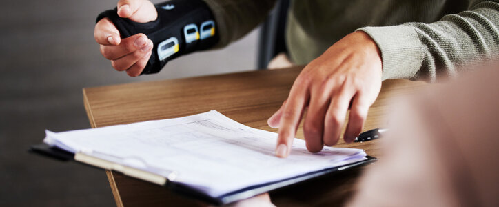 Man in a cast pointing to an insurance document.