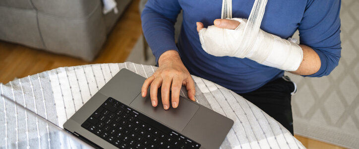 Man with an arm cast using the computer.